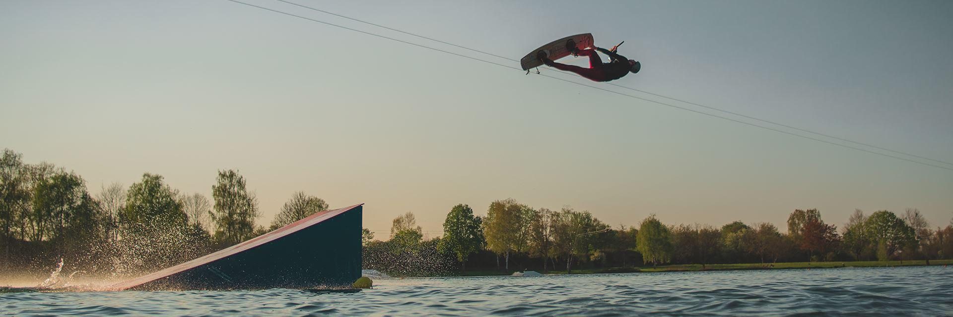 Wakeboarder springt über einen Kicker am Tunisee bei Sonnenuntergang